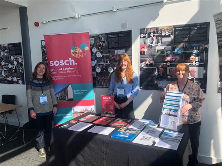 SOSCH and CHT team standing at conference table with flyers at Community Land Scotland conference